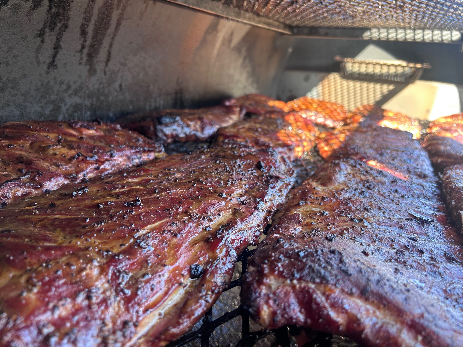 Spare ribs with a deep mahogany bark on the smoker grate